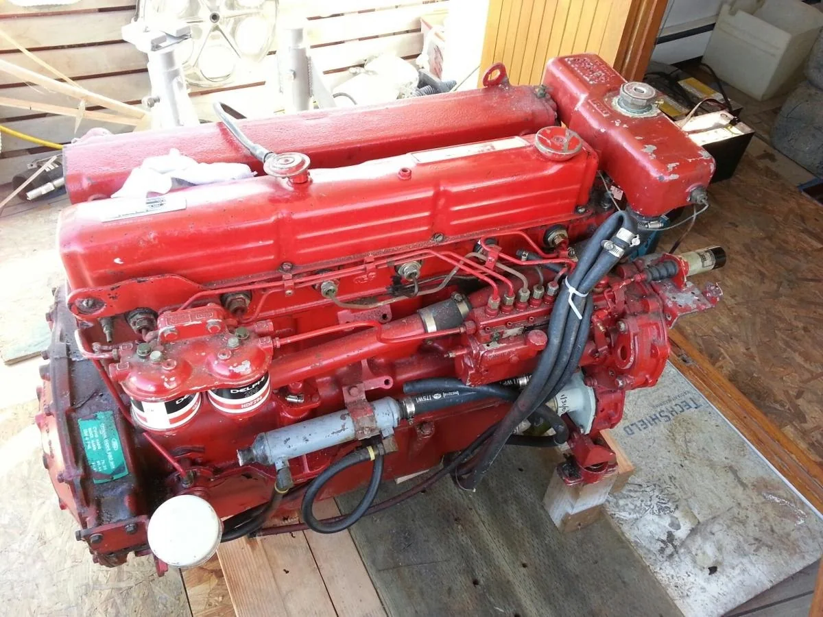 A red Ford Lehman 120 diesel engine, six cylinders in line, with the injection pump, fuel lines and heat exchanger visible