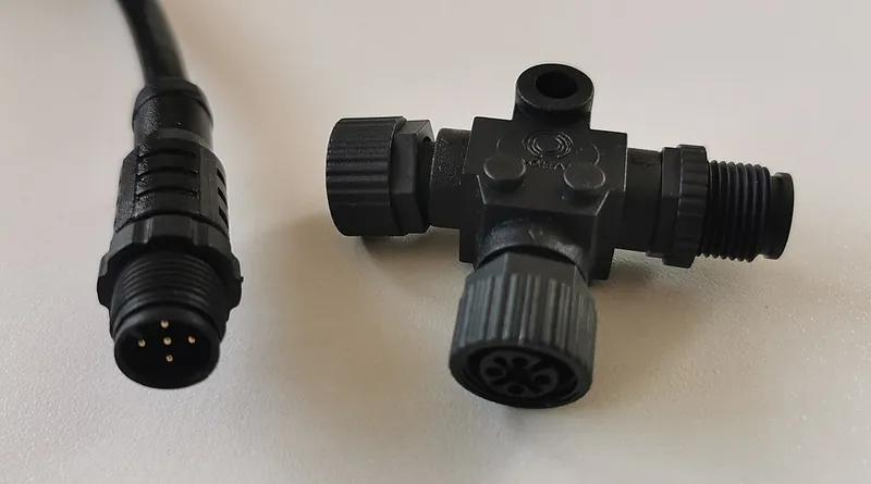 An NMEA 2000 Micro-C cable end with five pins next to a black T-connector