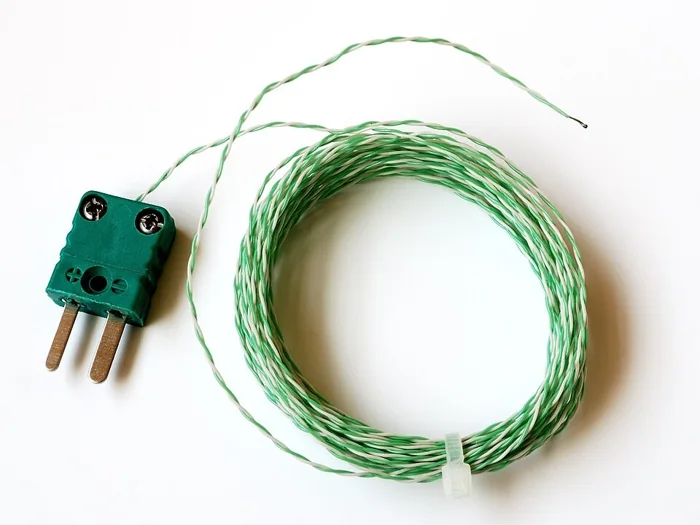 A K-type thermocouple: a coil of green and white twisted wire with a two-pin connector